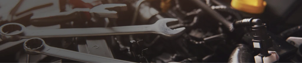 Maul- und Ringschlüssel auf einem geöffneten Automotor in einer Werkstatt